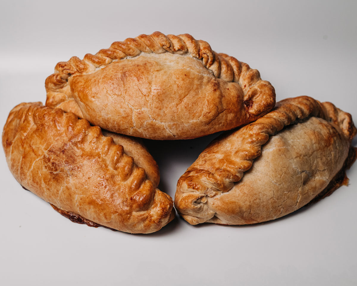 Three golden cheese and onion pasties ready for eating