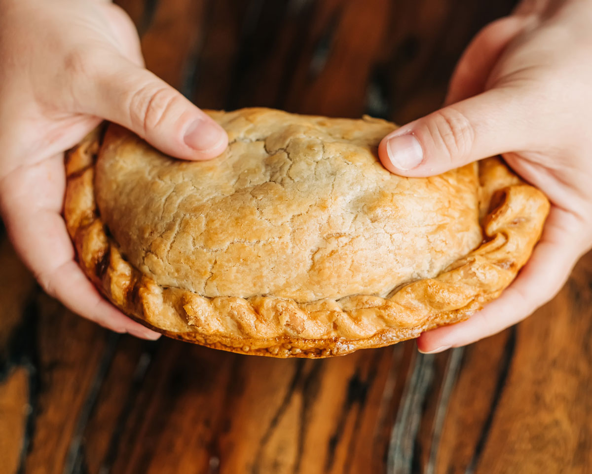 
                  
                    A woman holding a golden beef Cornish pasty
                  
                