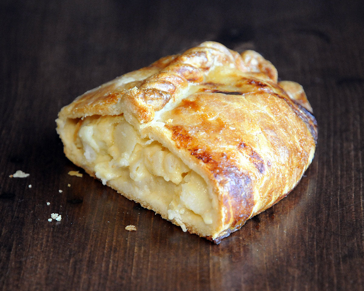A cheese and onion pasty cut in half to reveal its filling of potato, onion, cheddar cheese, and fontina cheese