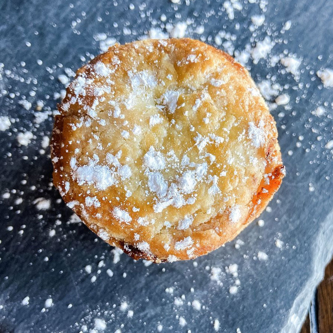 The top of a single mince pie, sprinkled with powdered sugar.