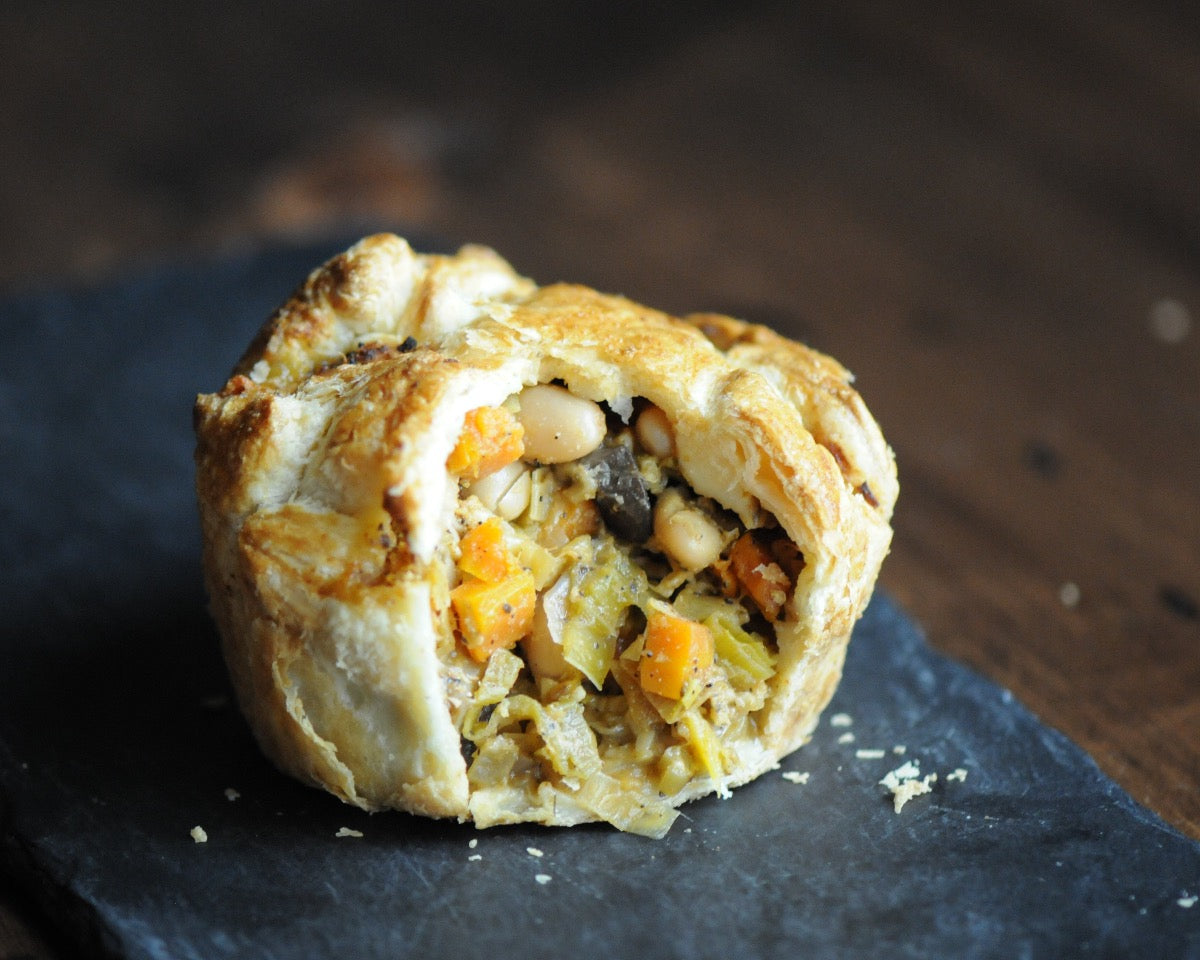 A golden mushroom and leek pie cut open to reveal its filling of mushroom, leek, shallot, carrot, celery, white bean, and fontina cheese