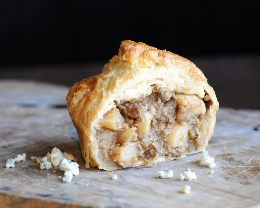 A British steak and ale pie cut in half to reveal its filling of steak, potato, mushroom, and Imported bleu cheese