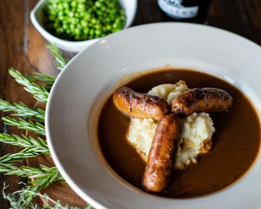 
                  
                    English bangers served with mash, gravy, and a bowl of garden peas
                  
                