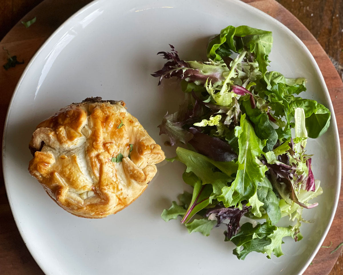 A golden samosa hand pie served with a mixed greens salad